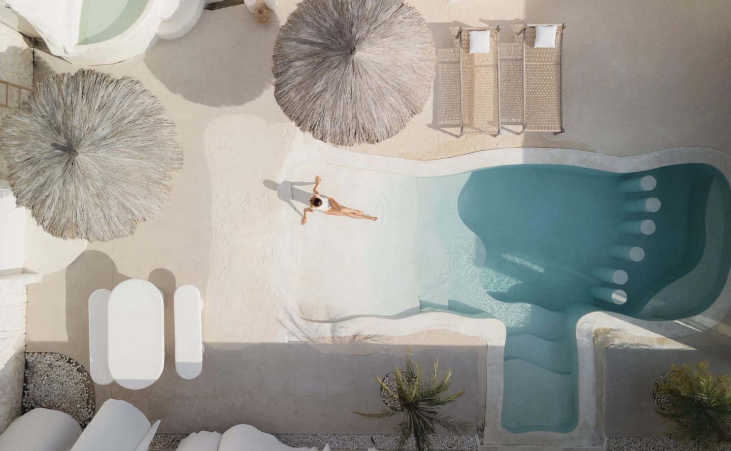 House of Creations Bali – Designer Villa Aerial Pool and Courtyard Scene Aerial view of luxury villa pool and sunbeds, thatched umbrellas, modern outdoor lounge and courtyard at House of Creations Bali
