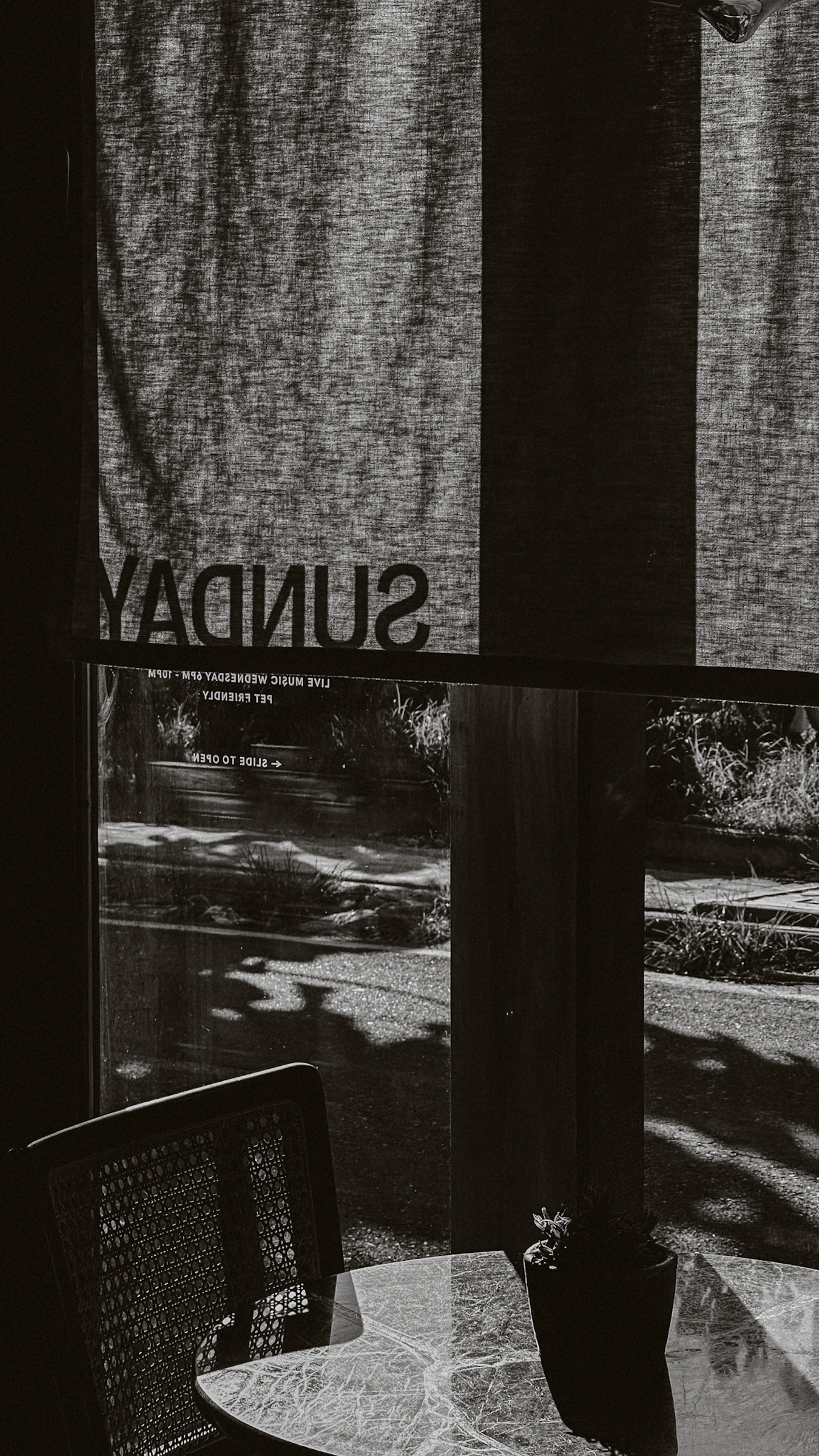 Black and white photo of restaurant window with “Sunday” branding, reflecting visual identity and ambiance for Sunday Kitchen, Brazilian cuisine Canggu Bali