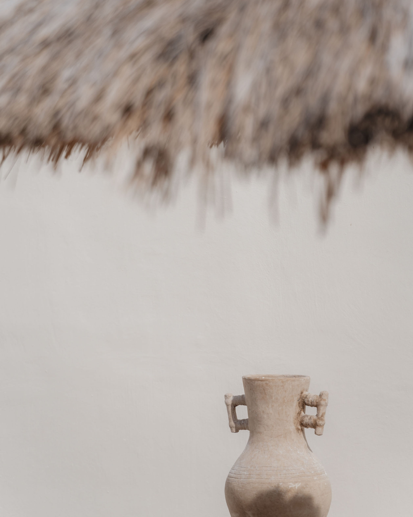 House of Creations Bali – Sculptural Vase and Natural Roof Detail Minimalist sculptural ceramic vase beneath textured thatched roof, featuring artisanal outdoor styling and villa branding at House of Creations Bali