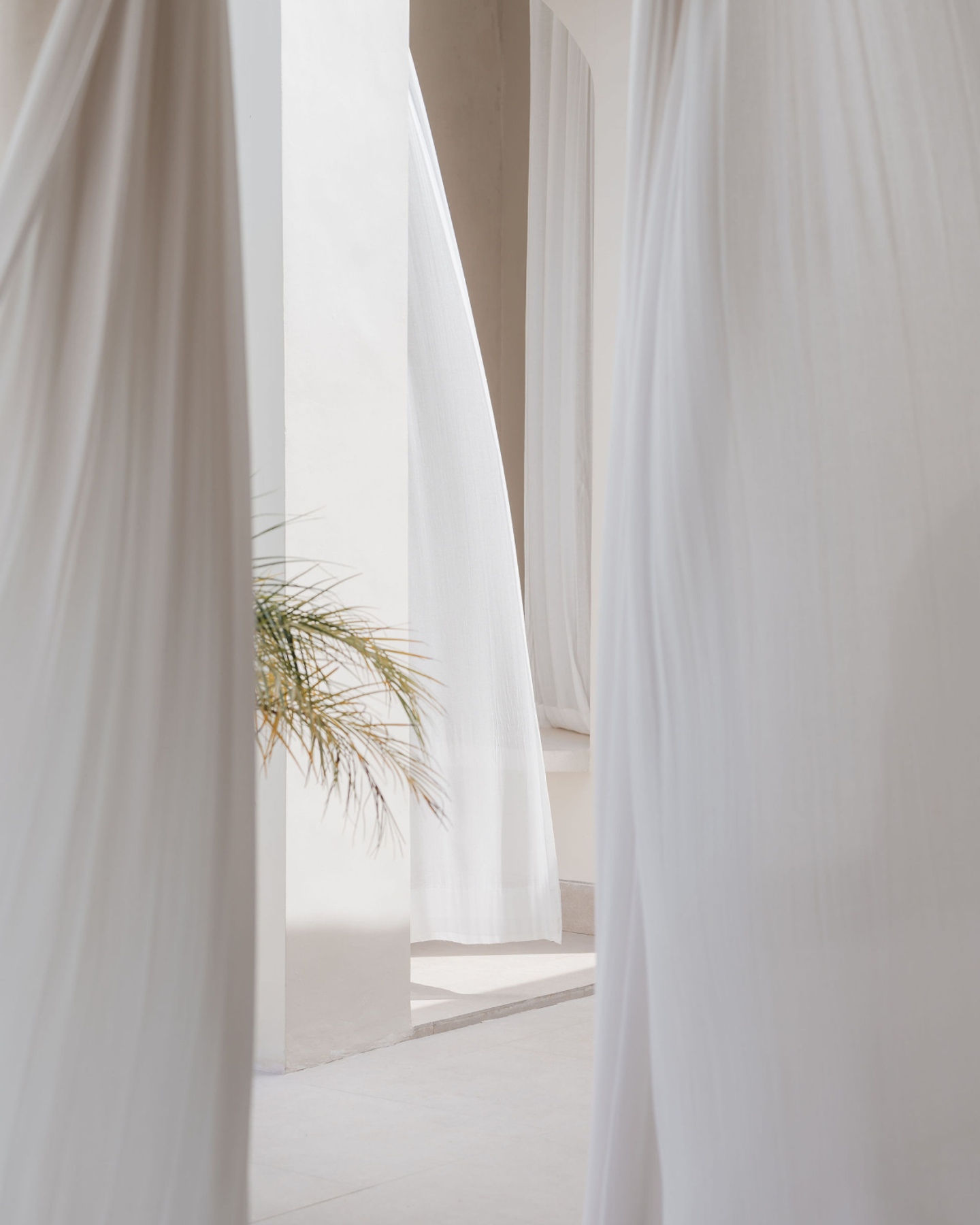 House of Creations Bali – Sheer Curtains and Soft Interior Light Flowing sheer curtains in sunlit villa interior, with subtle tropical foliage, expressing tranquility and designer branding for House of Creations Bali