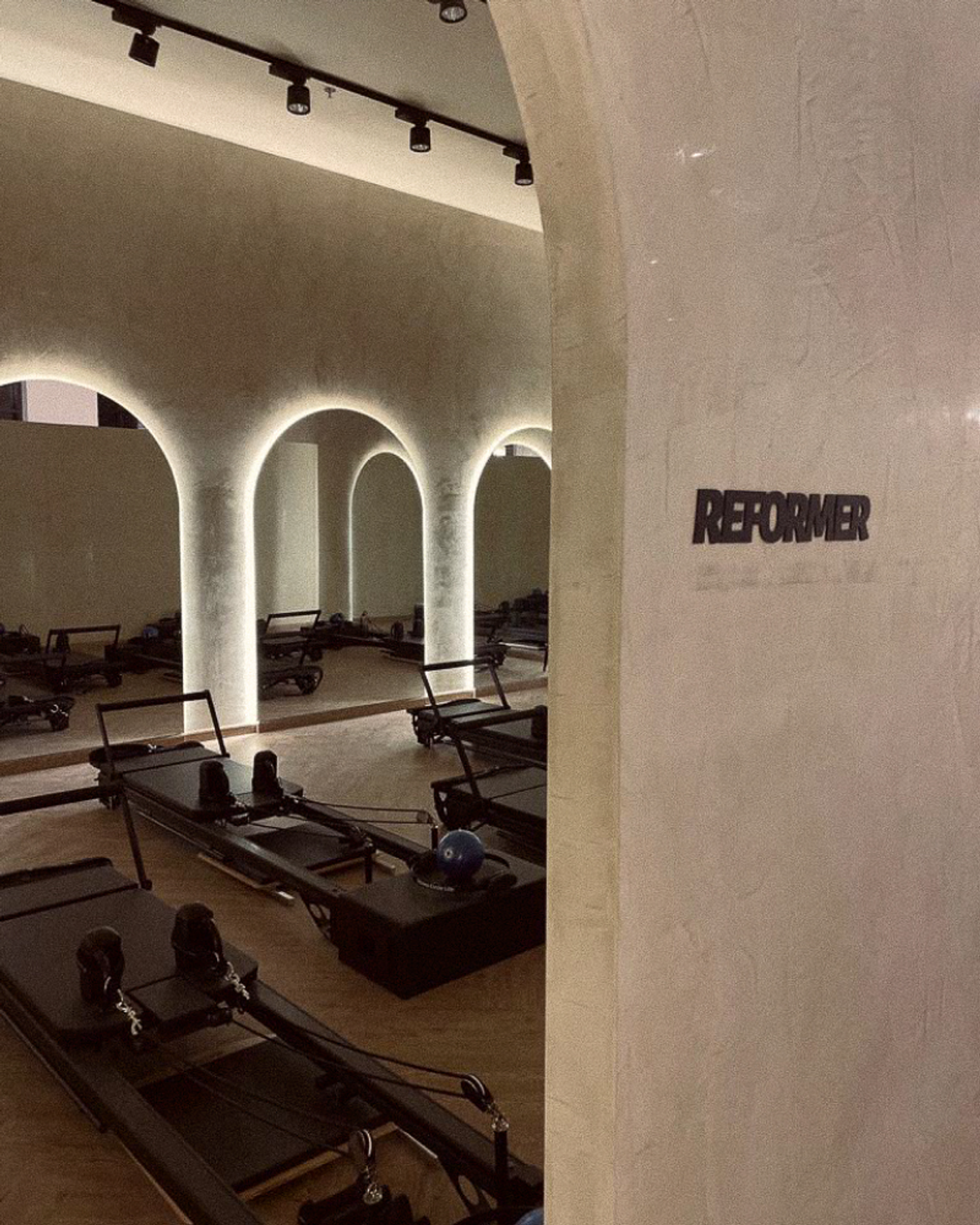 Posture Pilates Reformer Studio Signage – Interior Brand System Dubai Reformer studio view with arched columns and wall-mounted “REFORMER” sign, illustrating Posture Pilates interior signage and brand system in Dubai