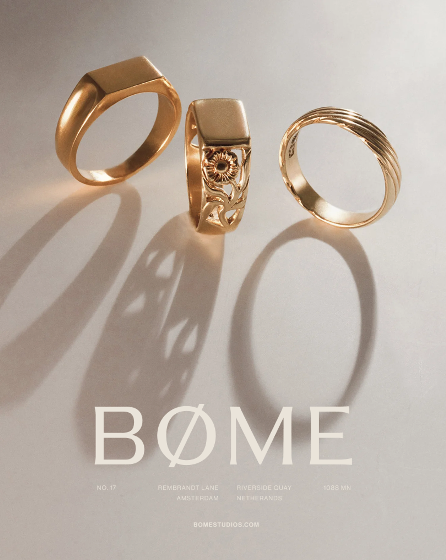Three gold BØME Studios rings standing in soft light with elongated shadows and the brand wordmark below, refined mens jewelry campaign visual and brand photography direction created by Eeze Studio for the Amsterdam-based label.