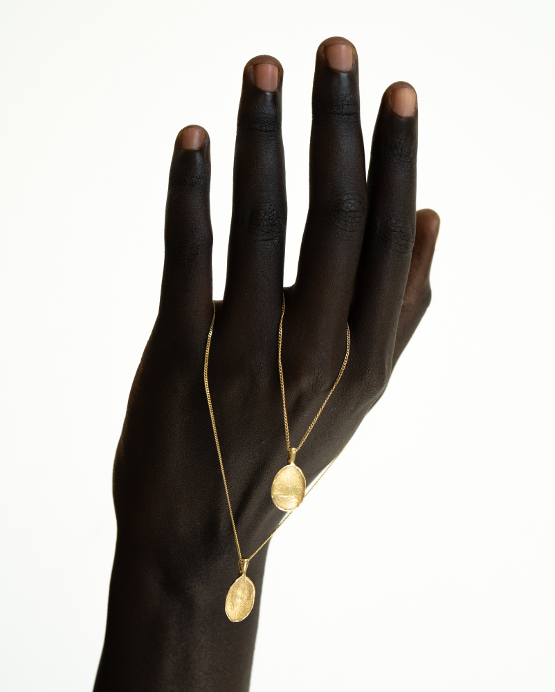 OMOI Jewelry Forever Pendant—Branding & Shopify Website Design by Eeze Studio Close-up of a hand showcasing the OMOI Jewelry Forever Pendant, featuring elegant gold necklace design; branding and Shopify website developed by Eeze Studio for contemporary jewelry brands.