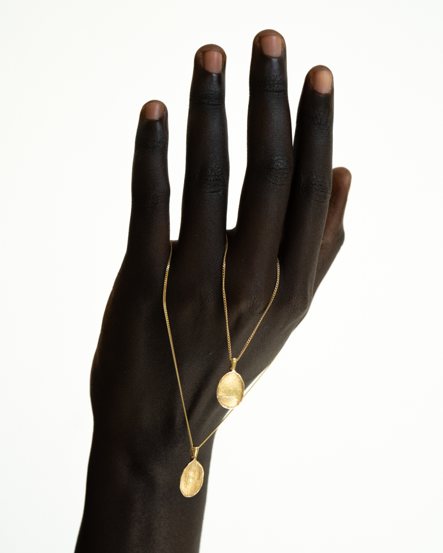Close-up of a hand showcasing the OMOI Jewelry Forever Pendant, featuring elegant gold necklace design; branding and Shopify website developed by Eeze Studio for contemporary jewelry brands.