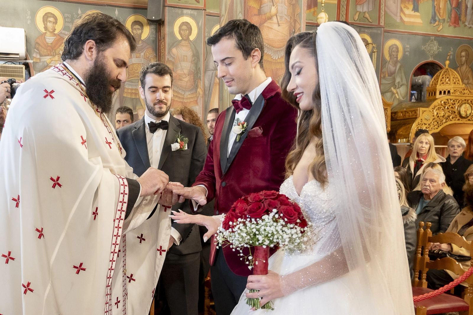The priest places the rings on the bride and groom in front of painted icons