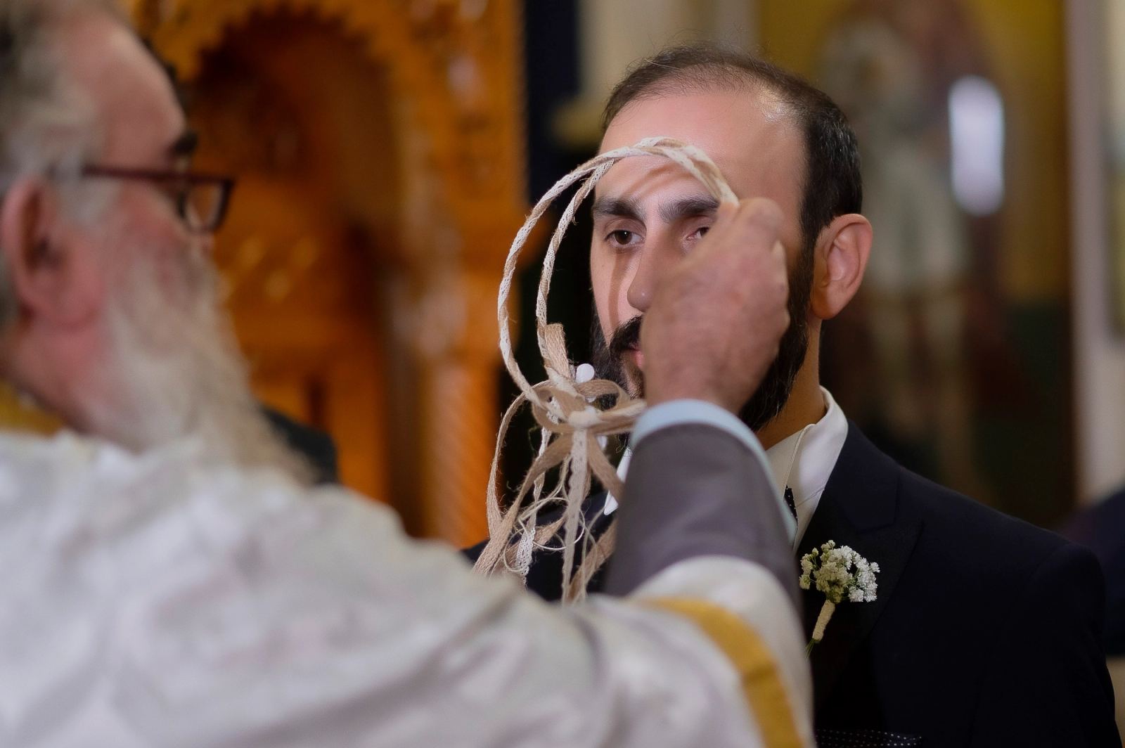 Ο ιερέας κρατά τα στέφανα μπροστά στο πρόσωπο του γαμπρού κατά την τελετή.