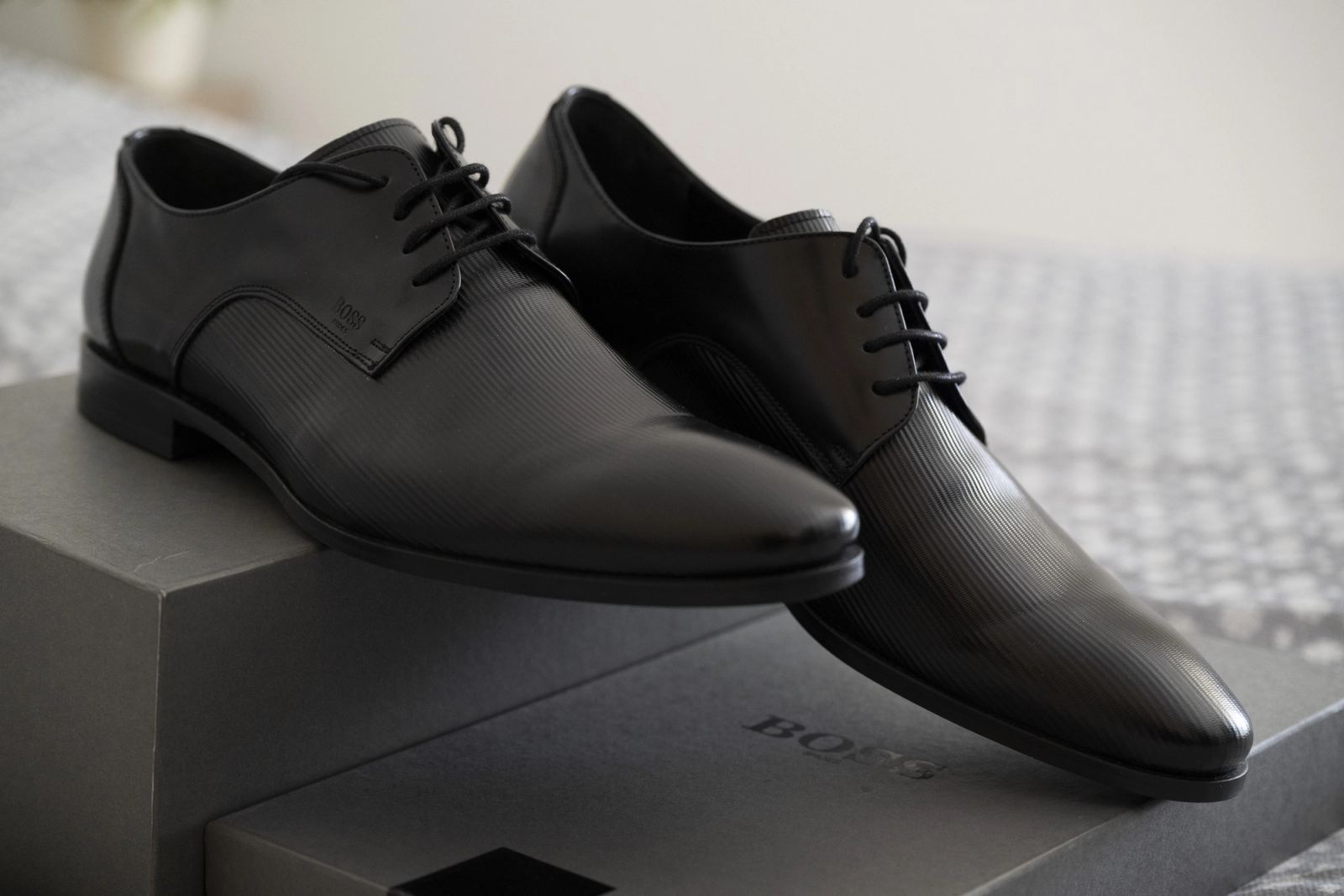 Black leather lace-up men's shoes resting on grey shoe boxes