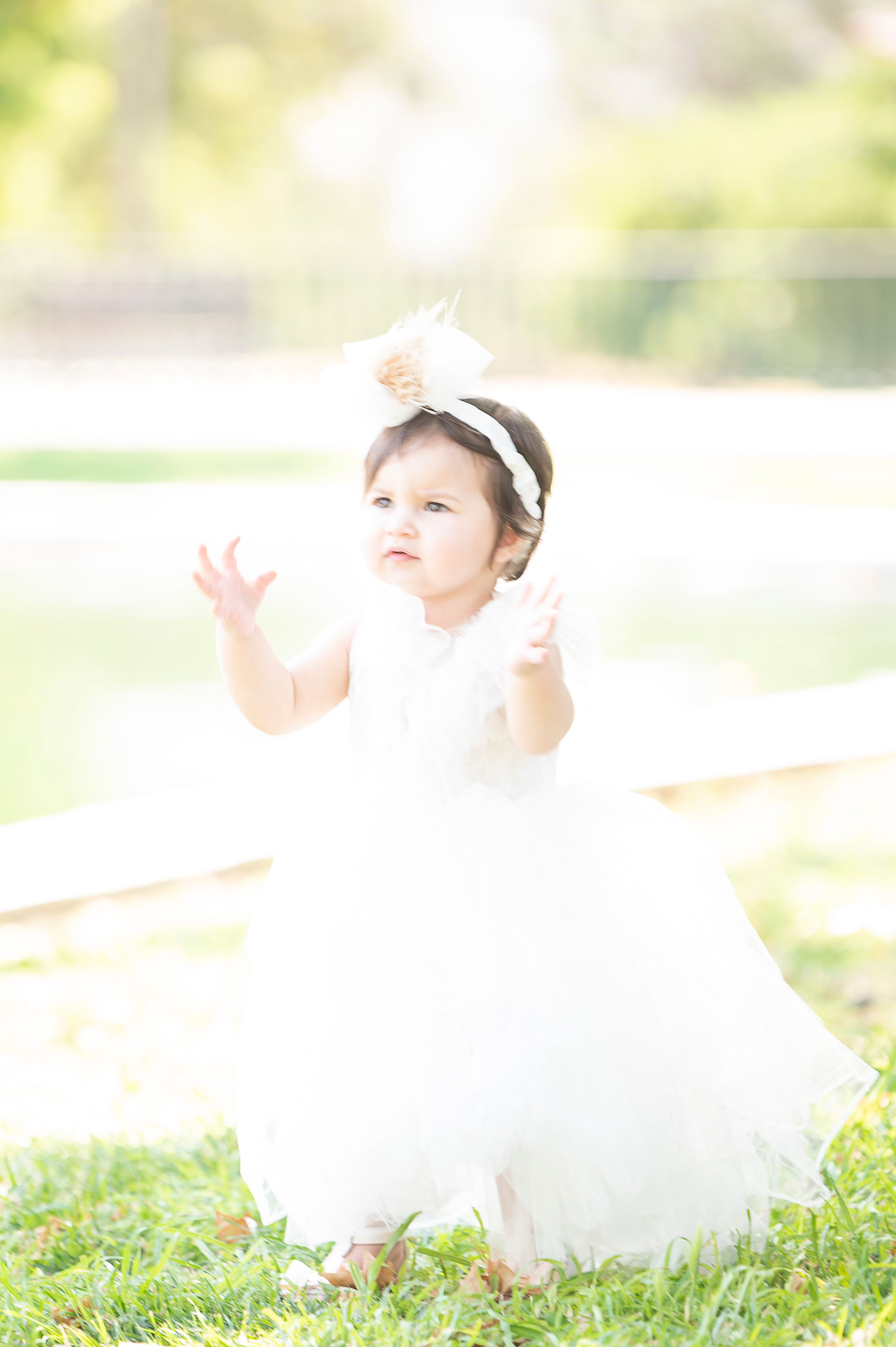 Little Danae, dressed in white, enjoys the warm summer light at Nea Filadelfeia Grove. A spontaneous moment filled with innocence and childhood joy, captured during her Next Day photoshoot.