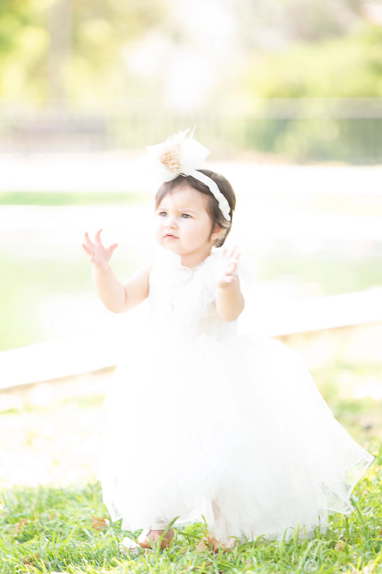 Little Danae, dressed in white, enjoys the warm summer light at Nea Filadelfeia Grove. A spontaneous moment filled with innocence and childhood joy, captured during her Next Day photoshoot.