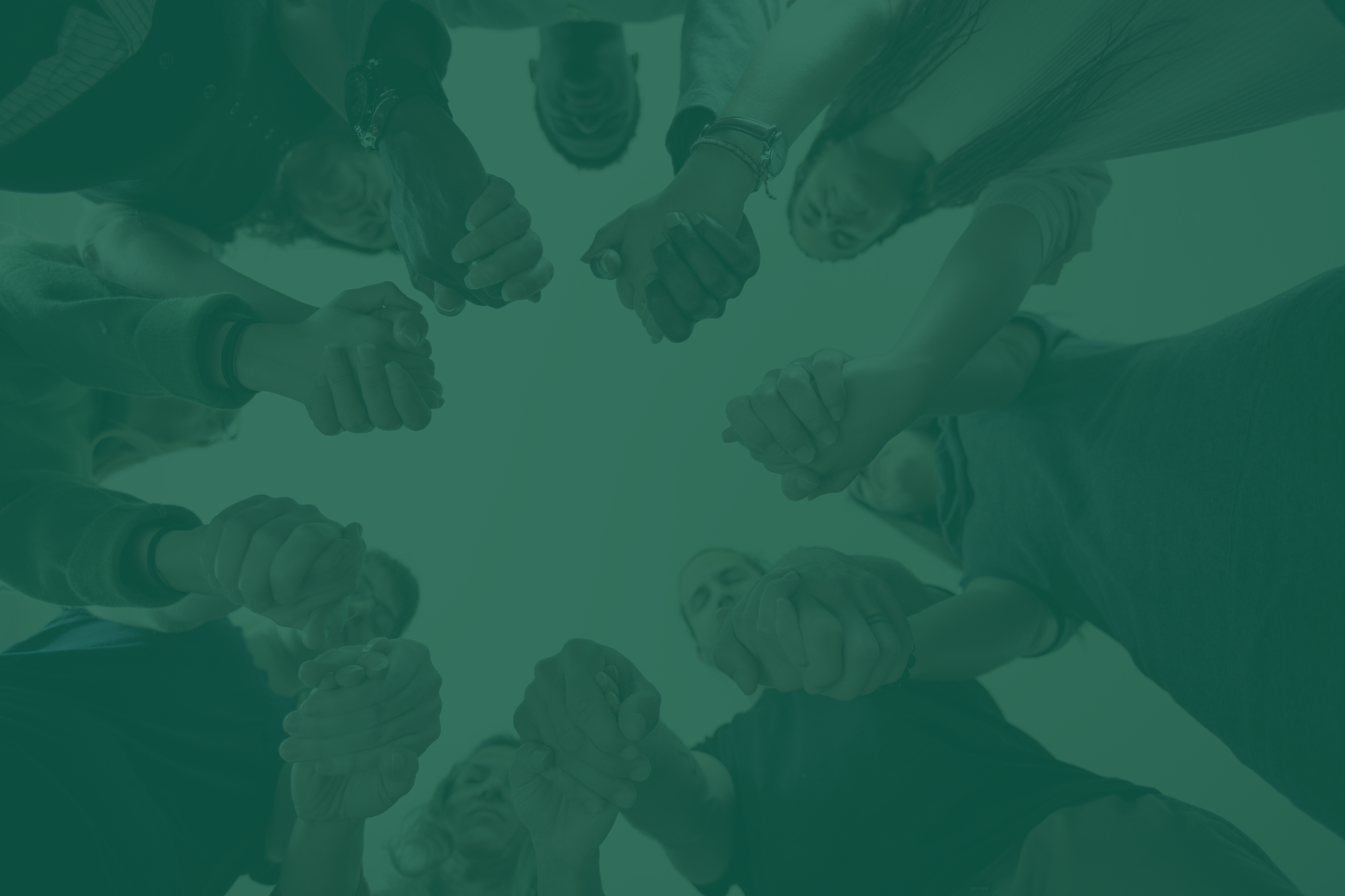 A circle of people standing together with hands clasped in prayer.