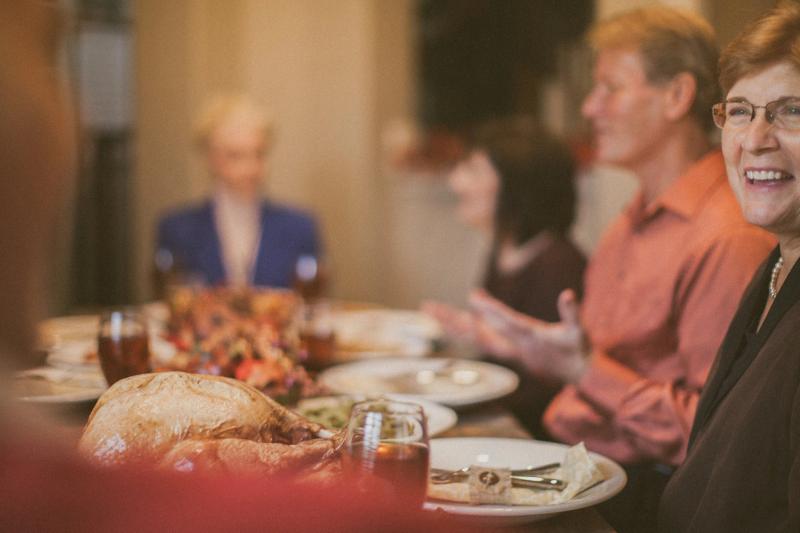 Three generations of a family talking and laughing around a dinner table