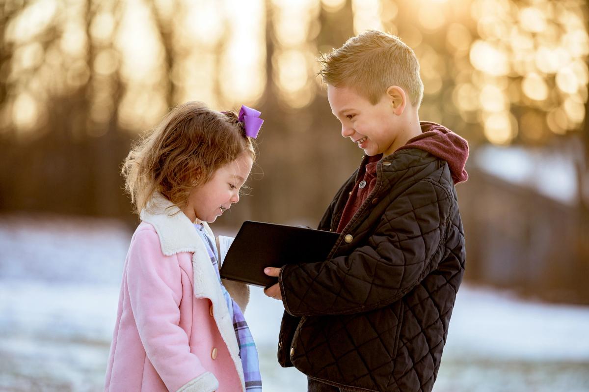 two children holding a bible in winter