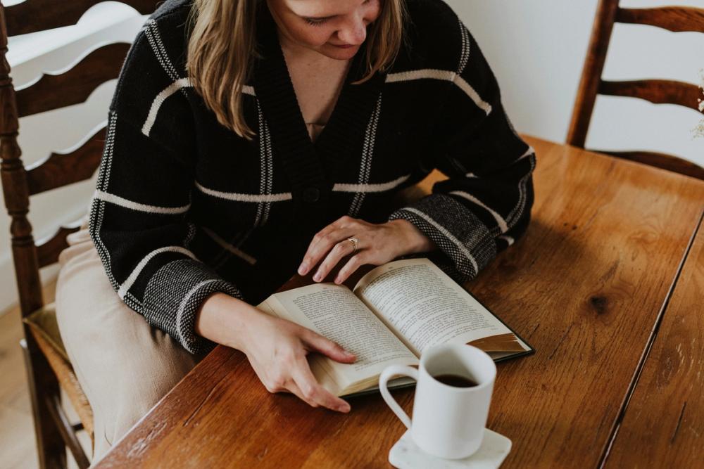 a woman reading a book with a cup of coffee