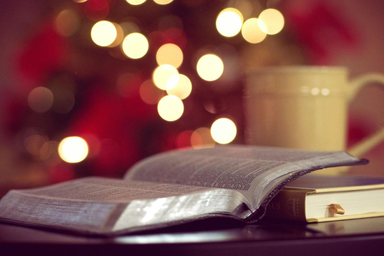 A classic Bible set against a Christmas lights backdrop