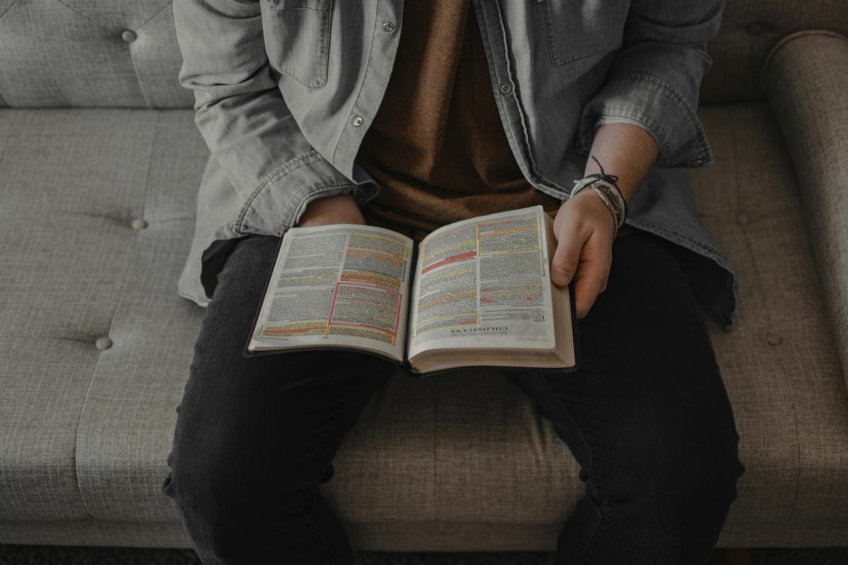 A man studying the bible on his sofa