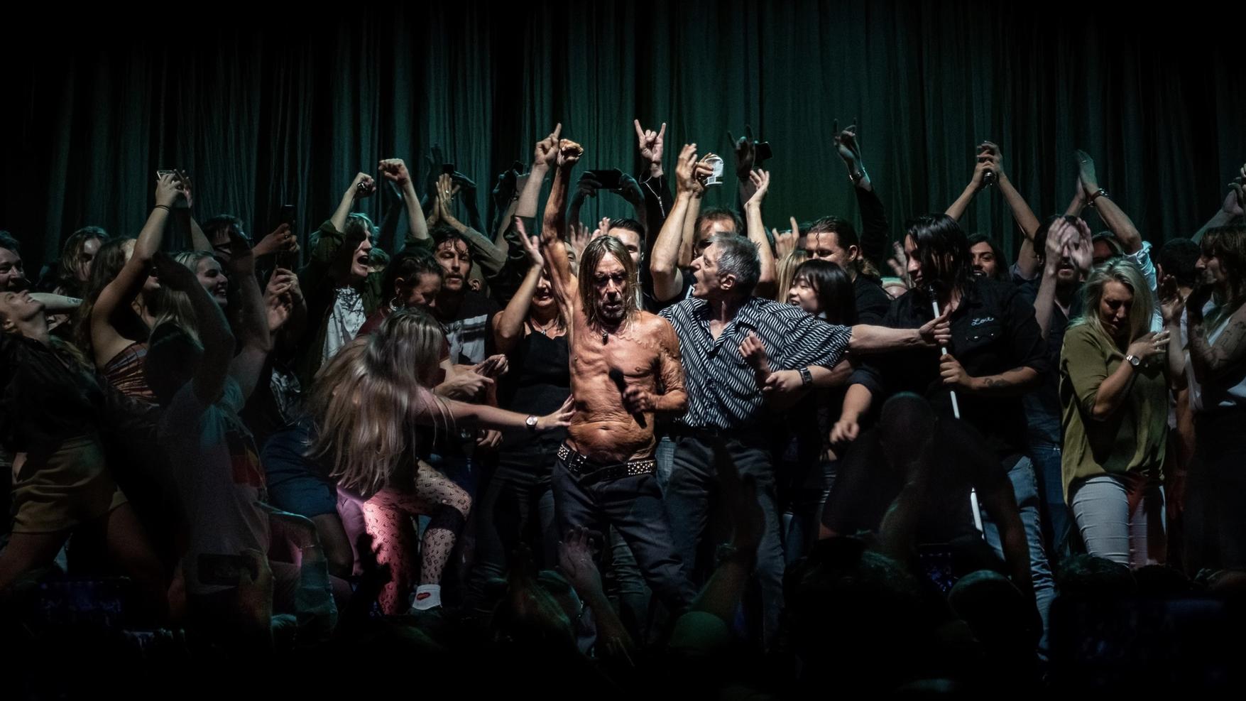 Iggy Pop surrounded by many people dancing