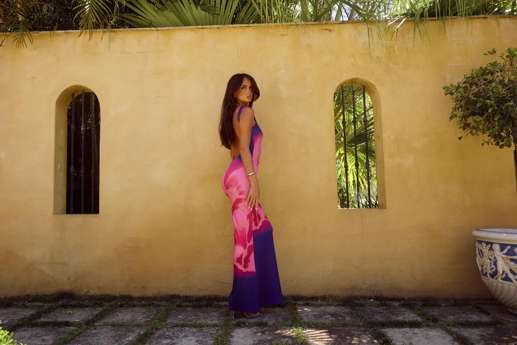 Woman in long floral dress in front of yellow wall