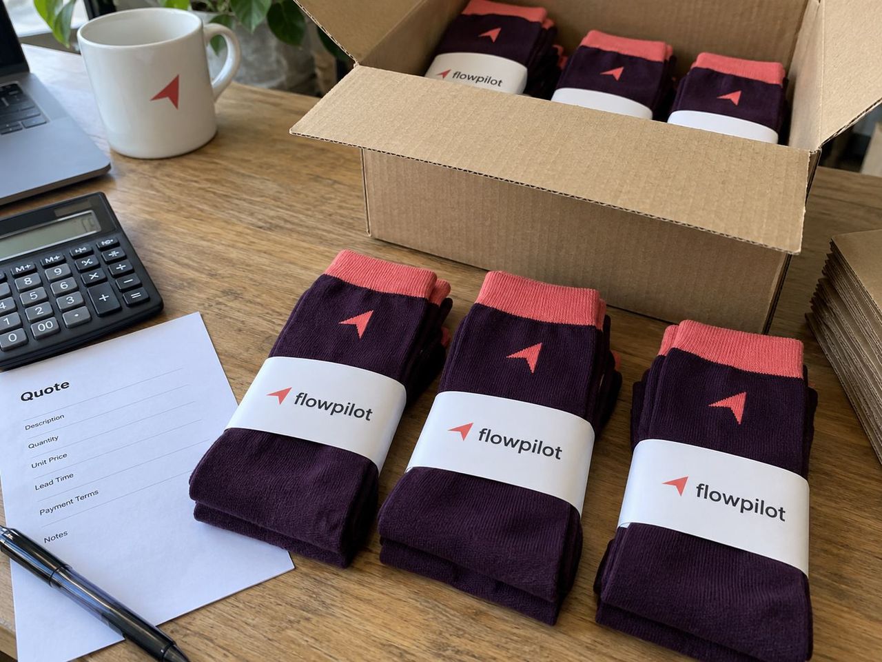 Custom socks with flowpilot paper bands packed in a cardboard box beside a quote sheet