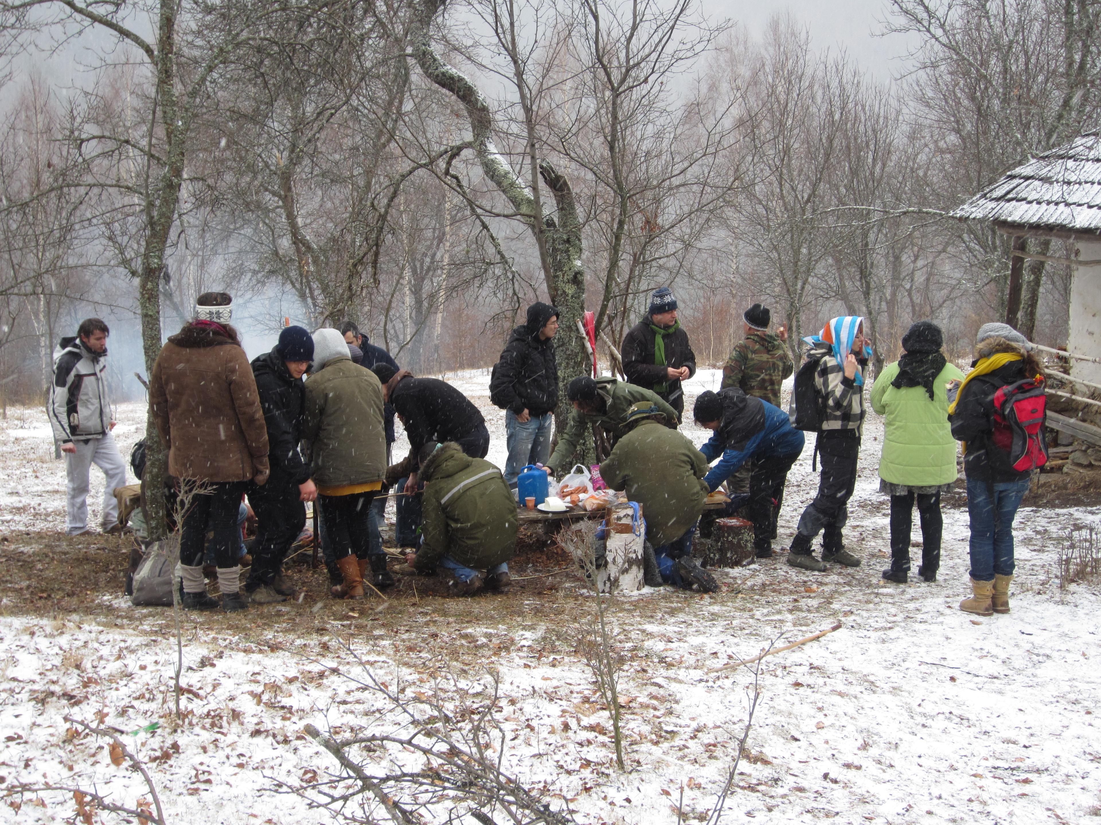 Group of people outdoors preparing food while it is snowing
