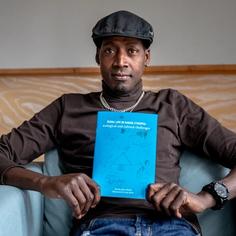 photo of A man holding a  book in hands and posing for camera 