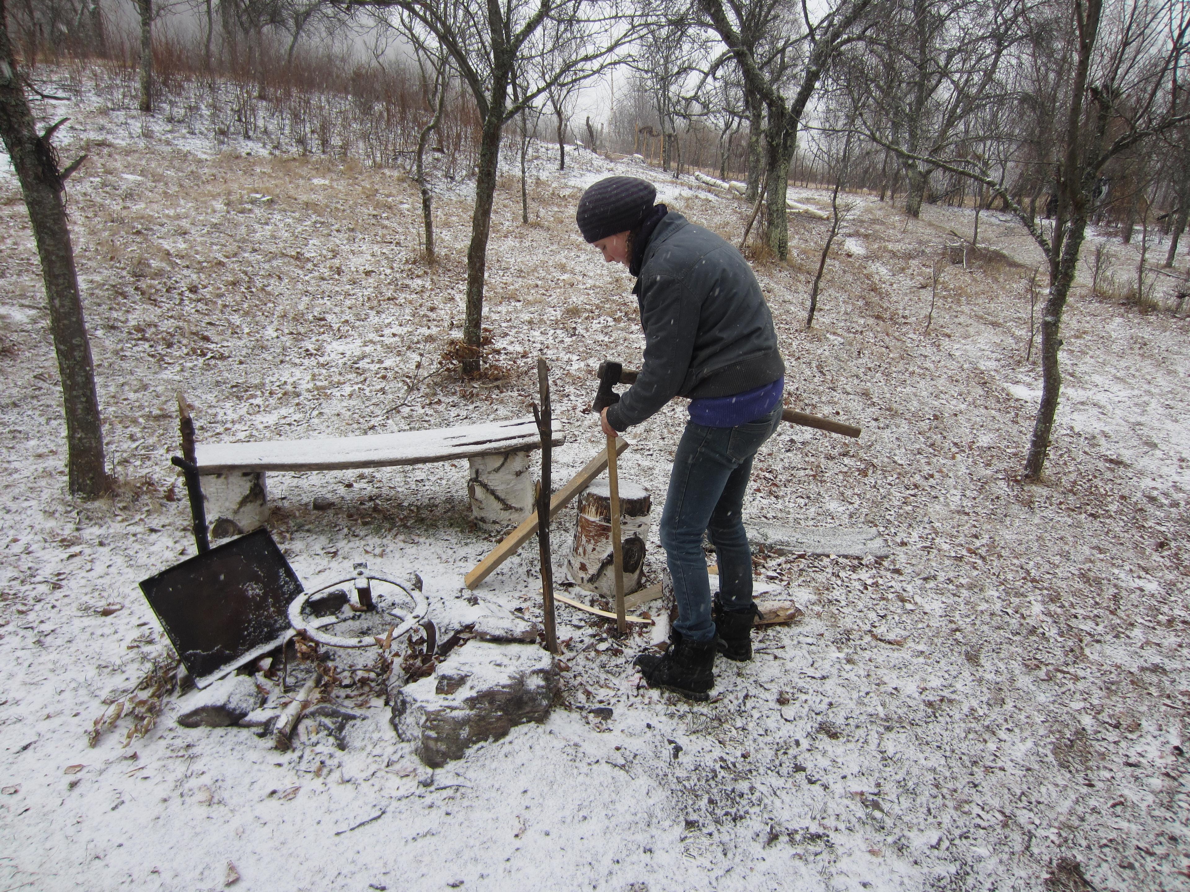 A woman is setting up a construction for bbq, outdoors in snow