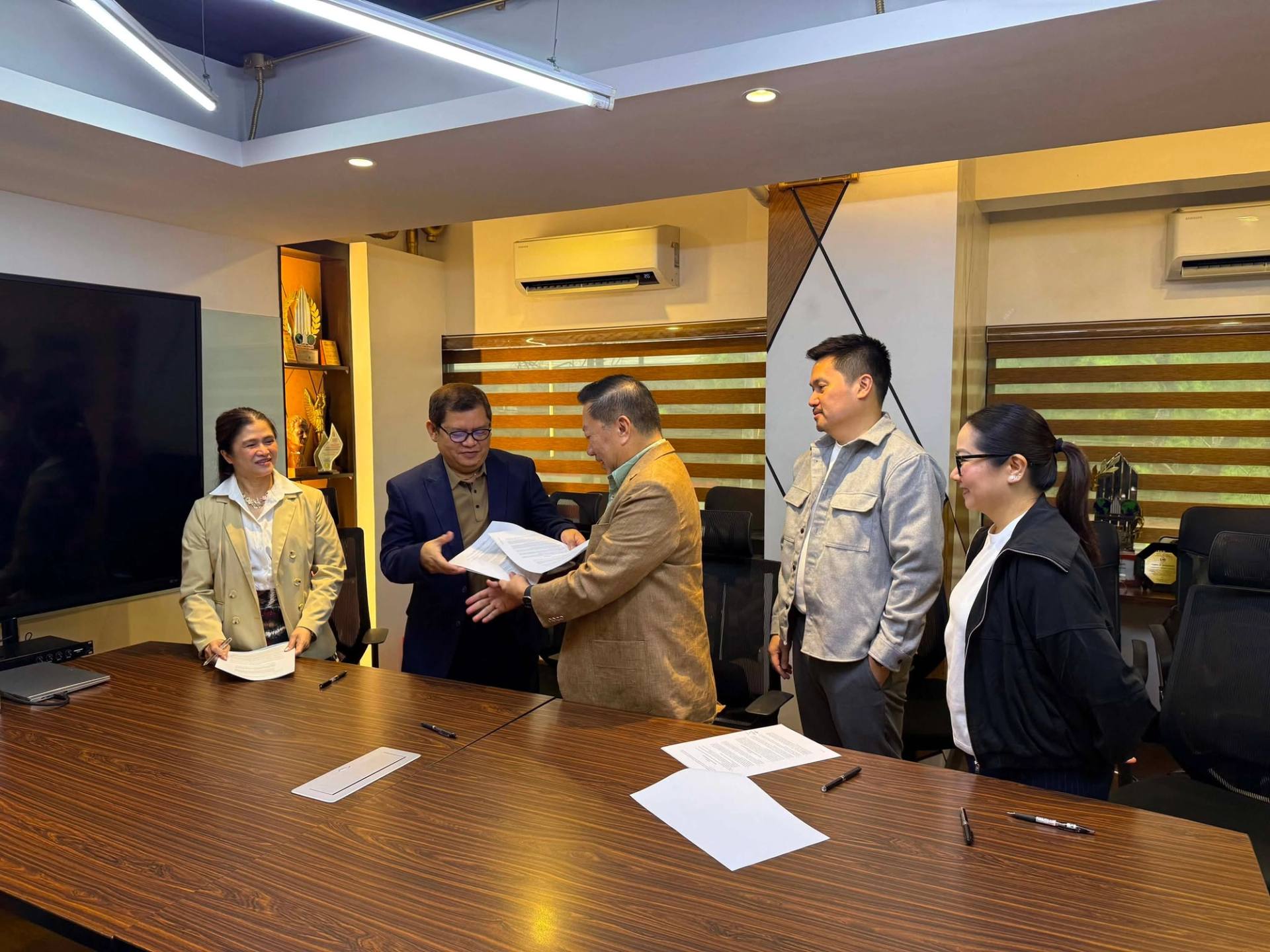 Architect Nestor Mangio of CCEI and Tristan Aparece of TCorp shake hands after signing the Fairway Residences agreement, witnessed by Amie Aparece, Brian Mangio and Hazel Mangio Paras.