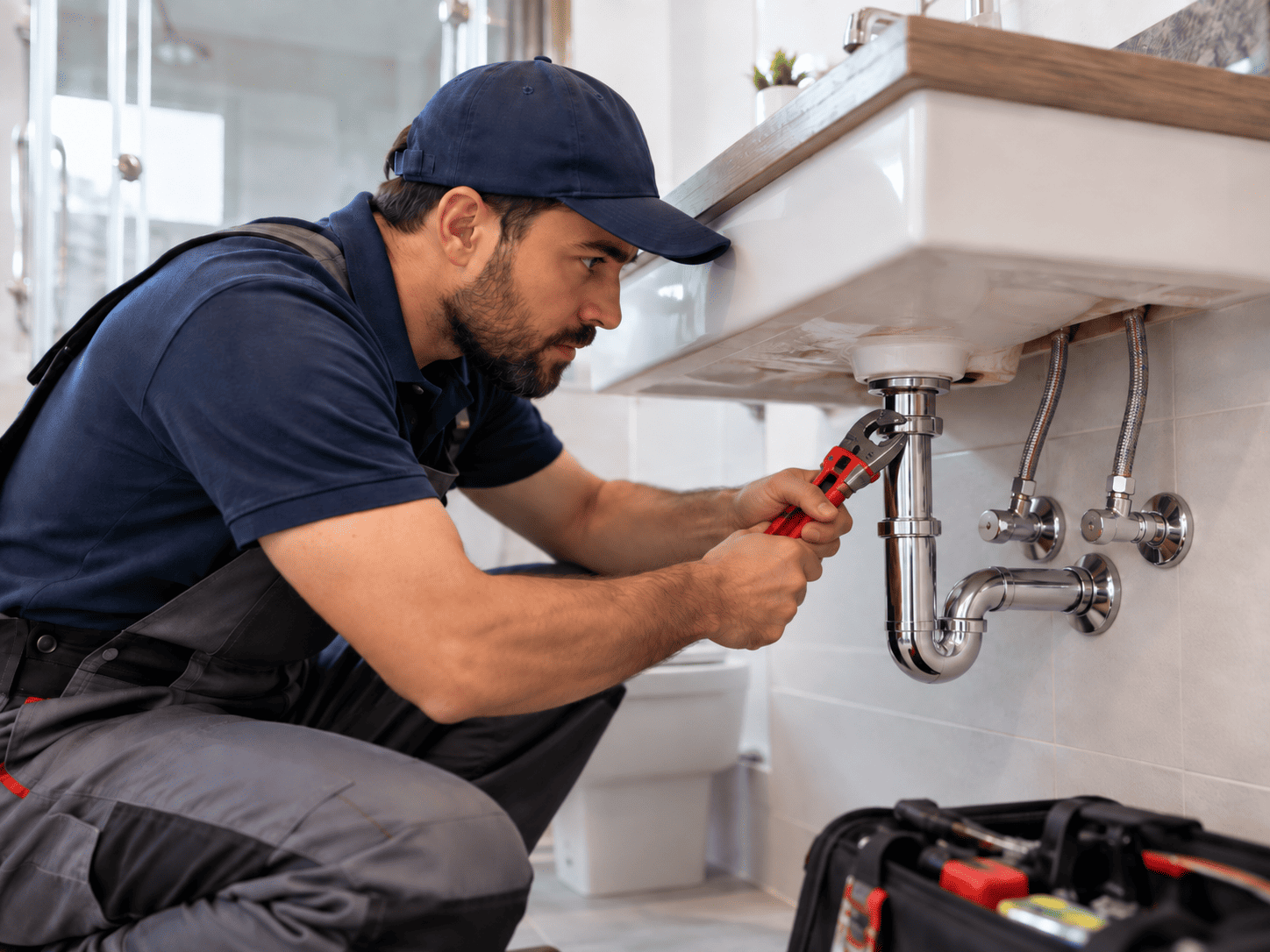 Técnico realizando trabajo de gasfitería en instalación de cañerías bajo lavamanos.