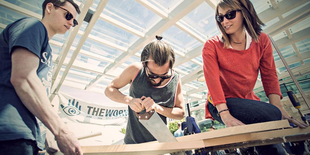 Three people sawing wood