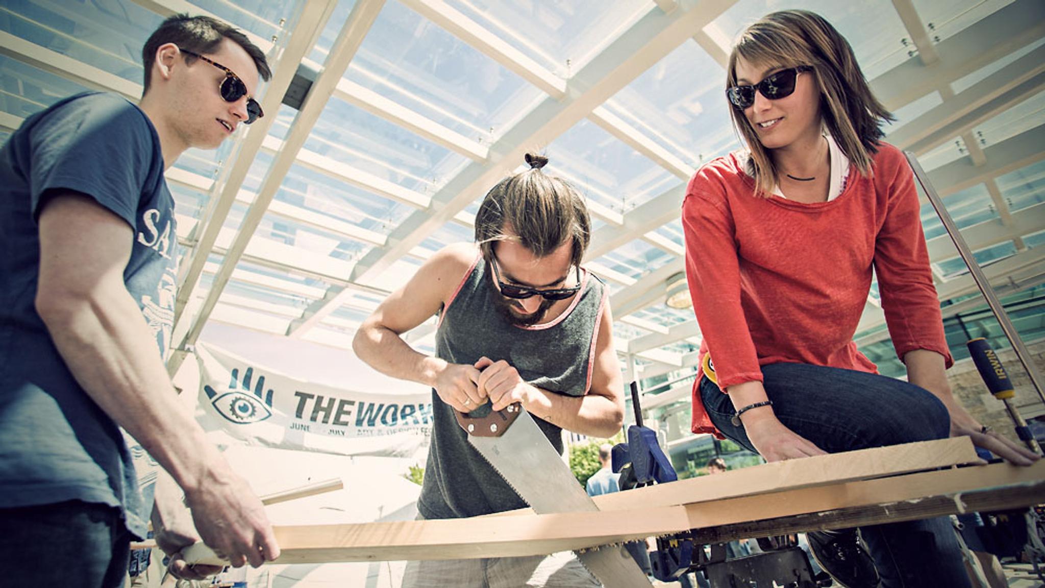 Three people sawing wood