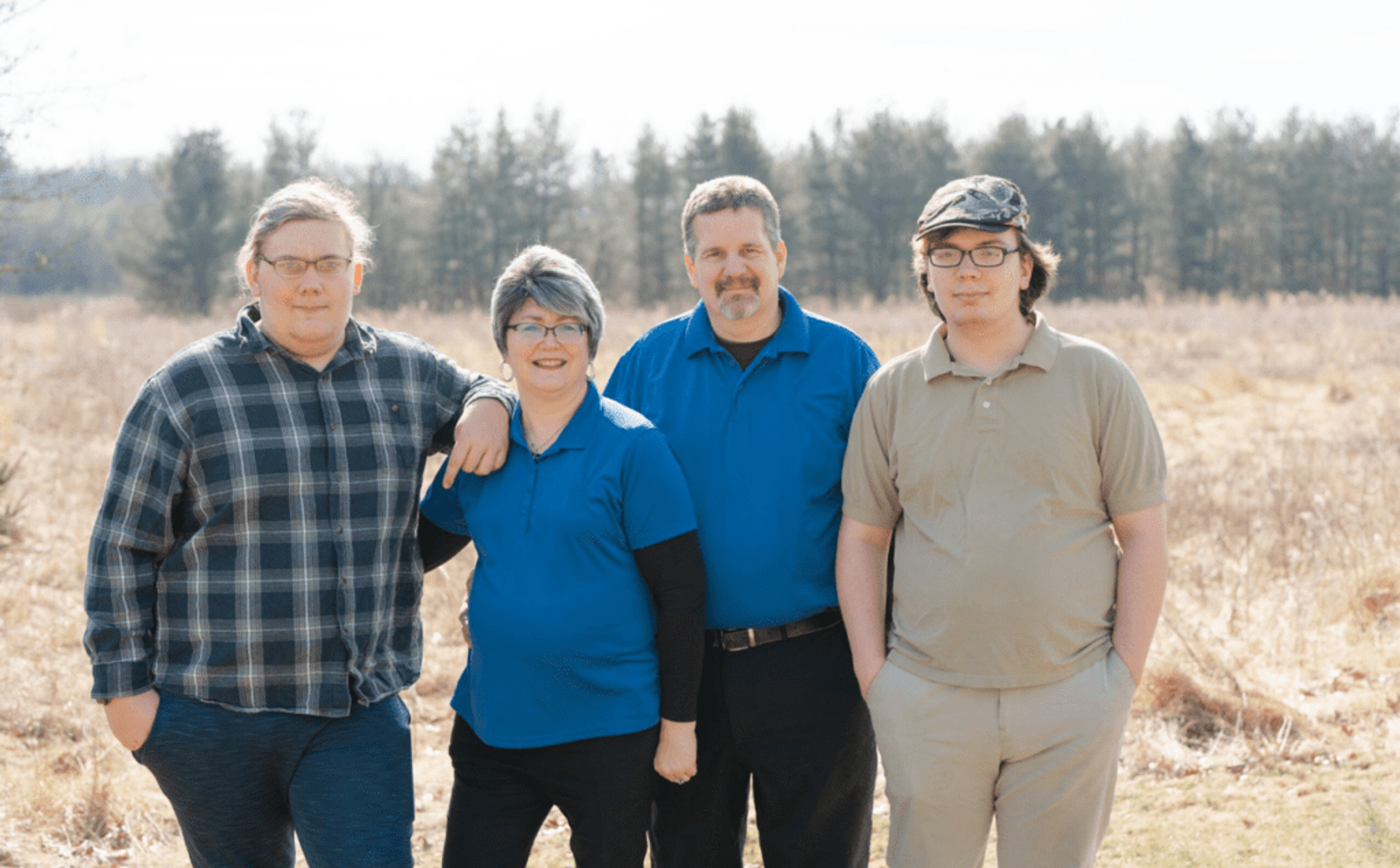 Parents with two teen sons, a field is in the background