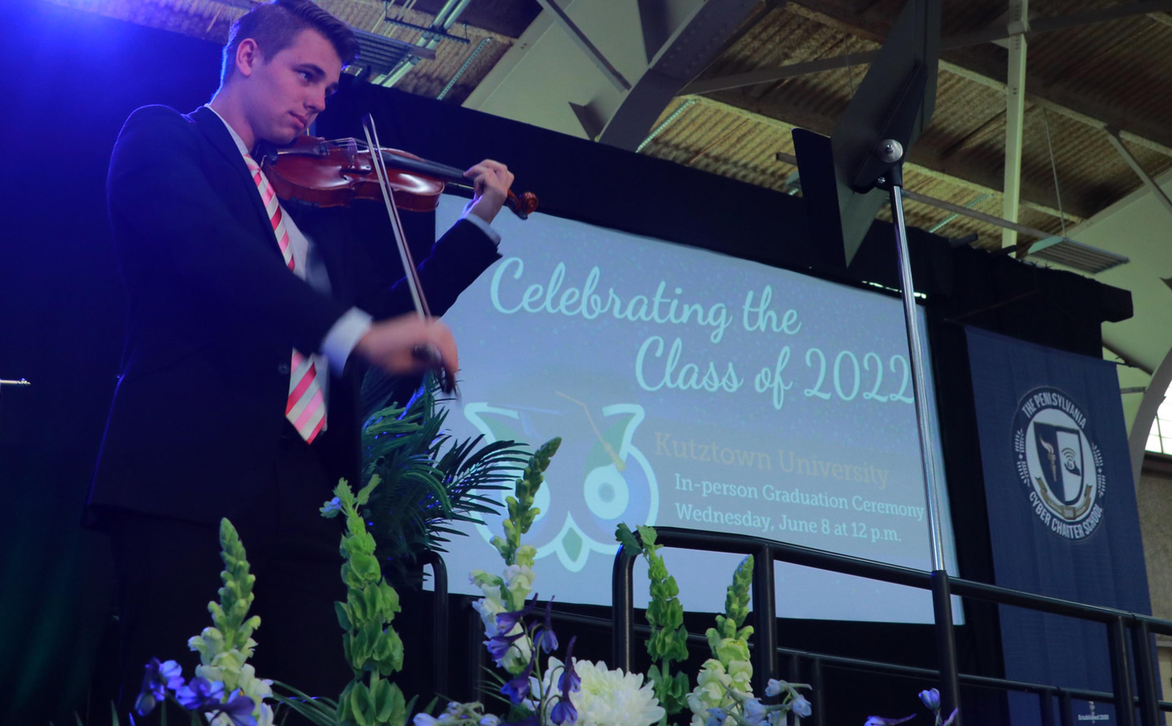 Student plays violin on stage at graduation ceremony.
