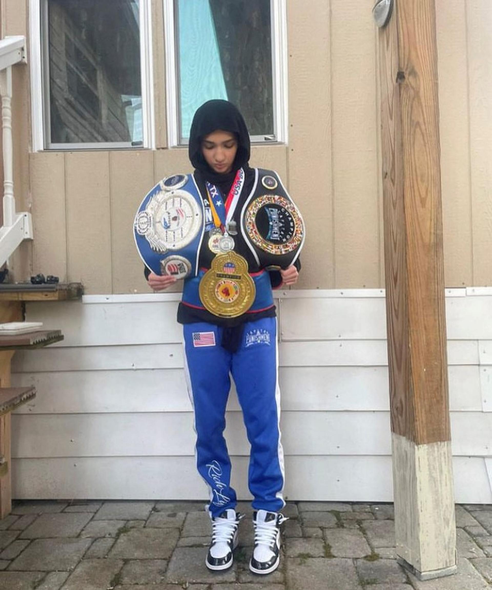 Aya poses with championship belts and medals. 