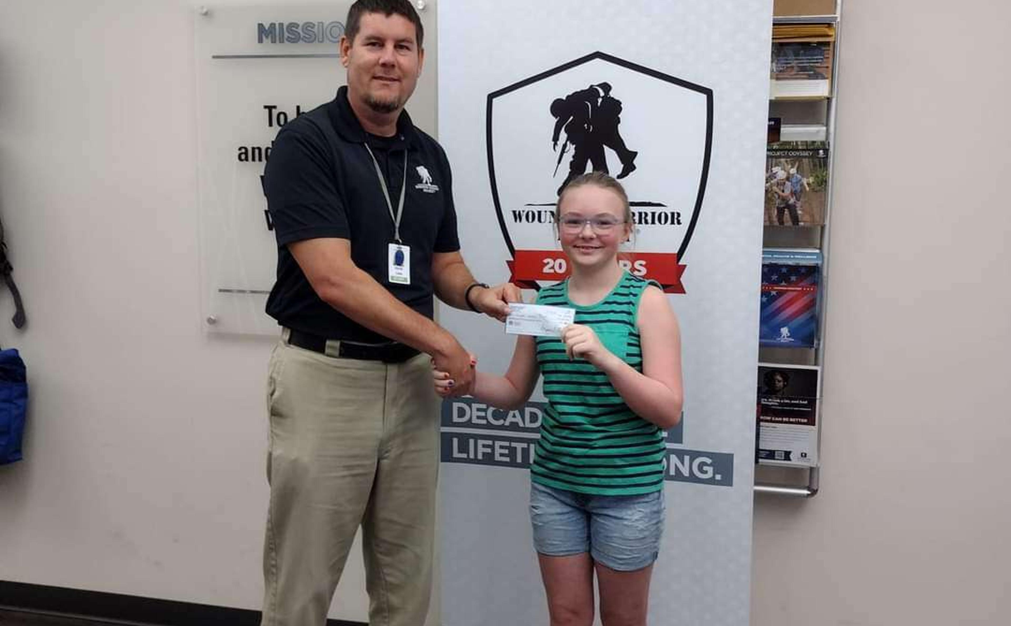 McKenna Miller of Renfrew, presents Dave Kane, of the Wounded Warrior Project, with a check for $1,200. 