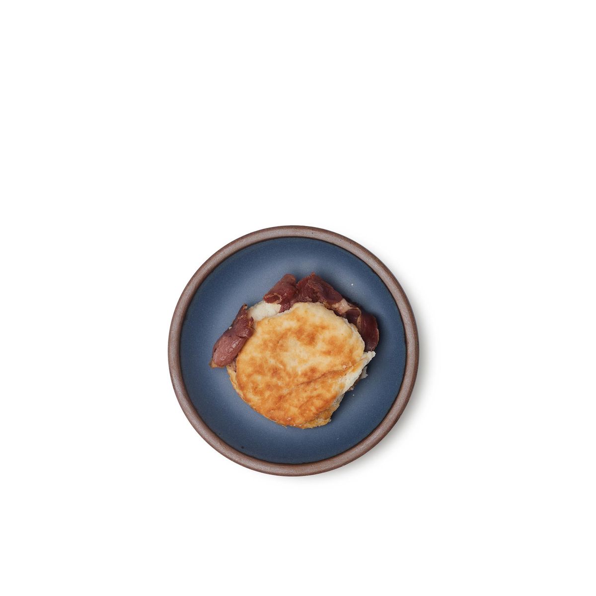 A breakfast sandwich on a dessert sized ceramic plate in a toned-down navy color featuring iron speckles and an unglazed rim.