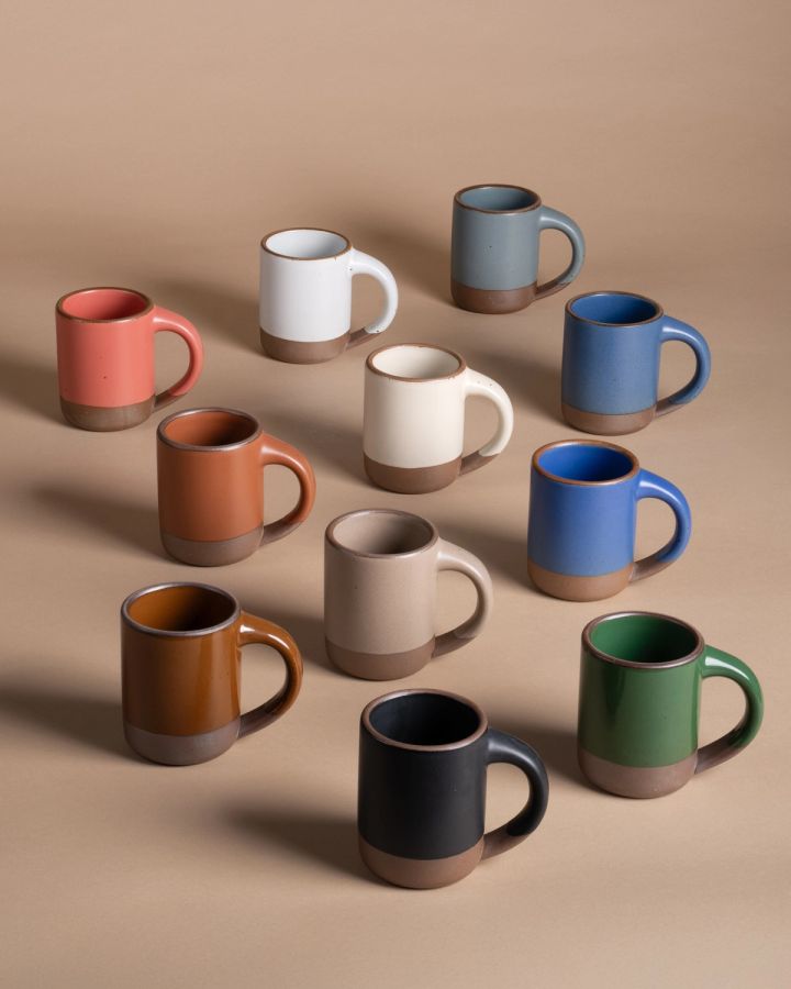 A lineup of ceramic mugs in a rainbow of different colors