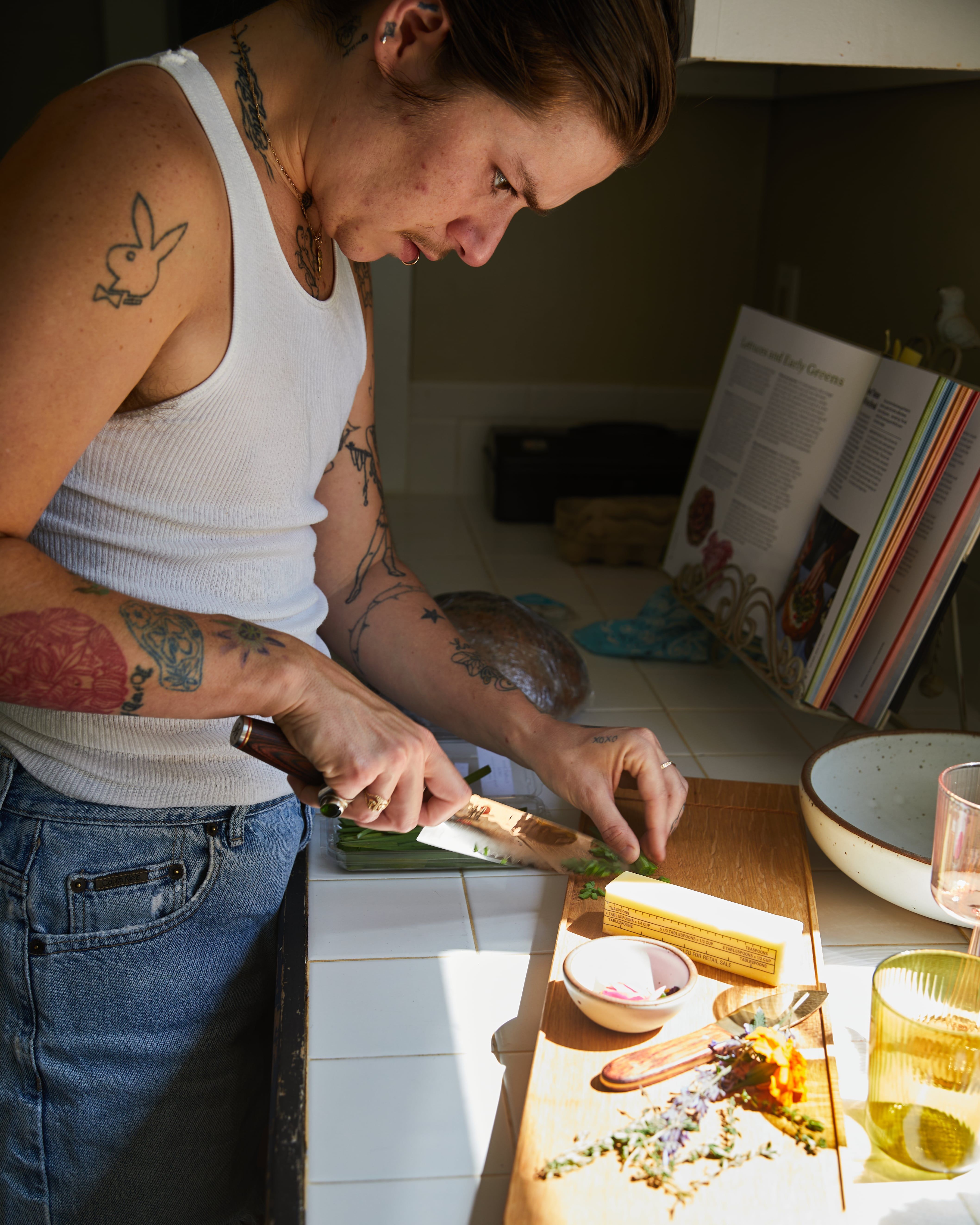 A person chops herbs on a board at the kitchen counter