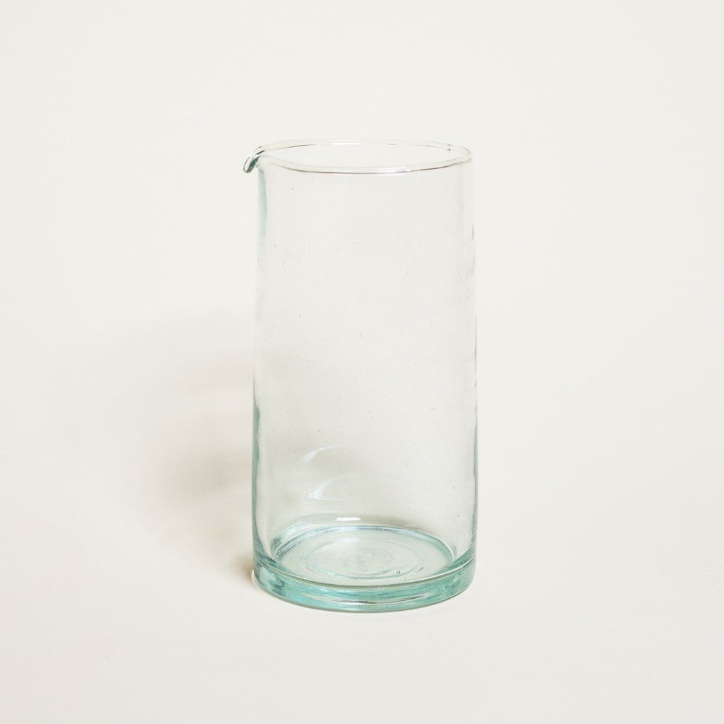 A tall clear glass pitcher that is empty