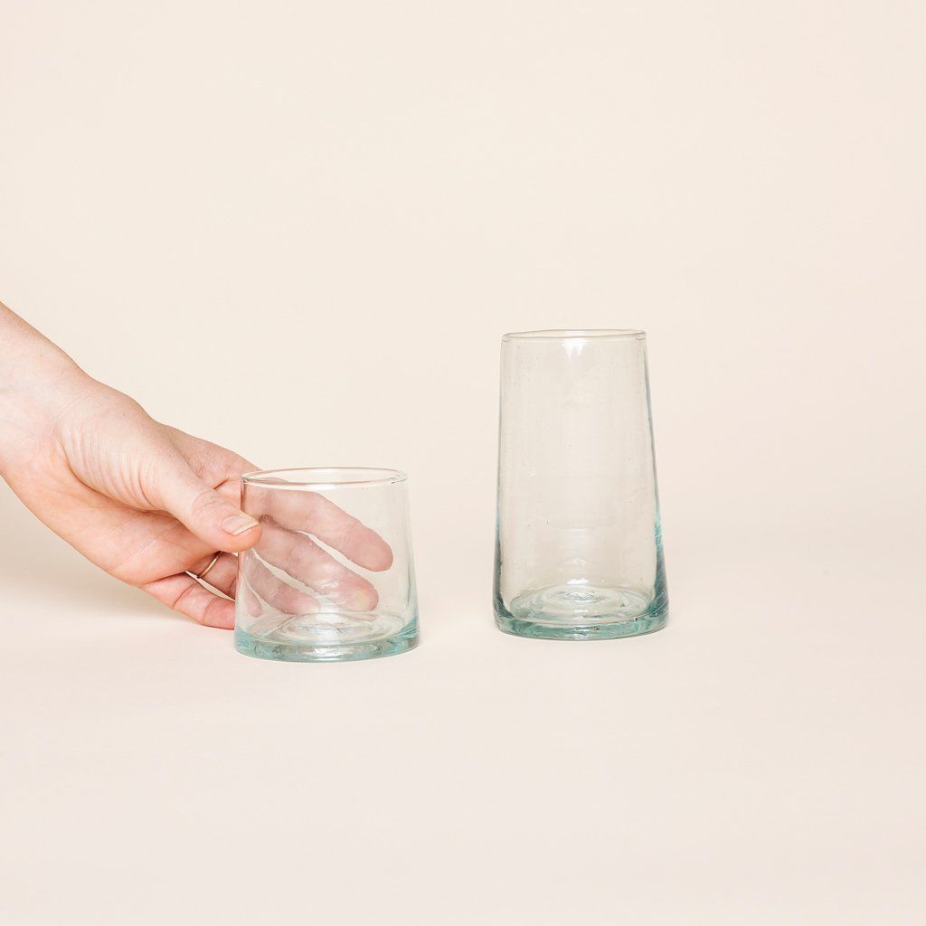 Hand holding medium recycled Moroccan glassware next to  tall version.