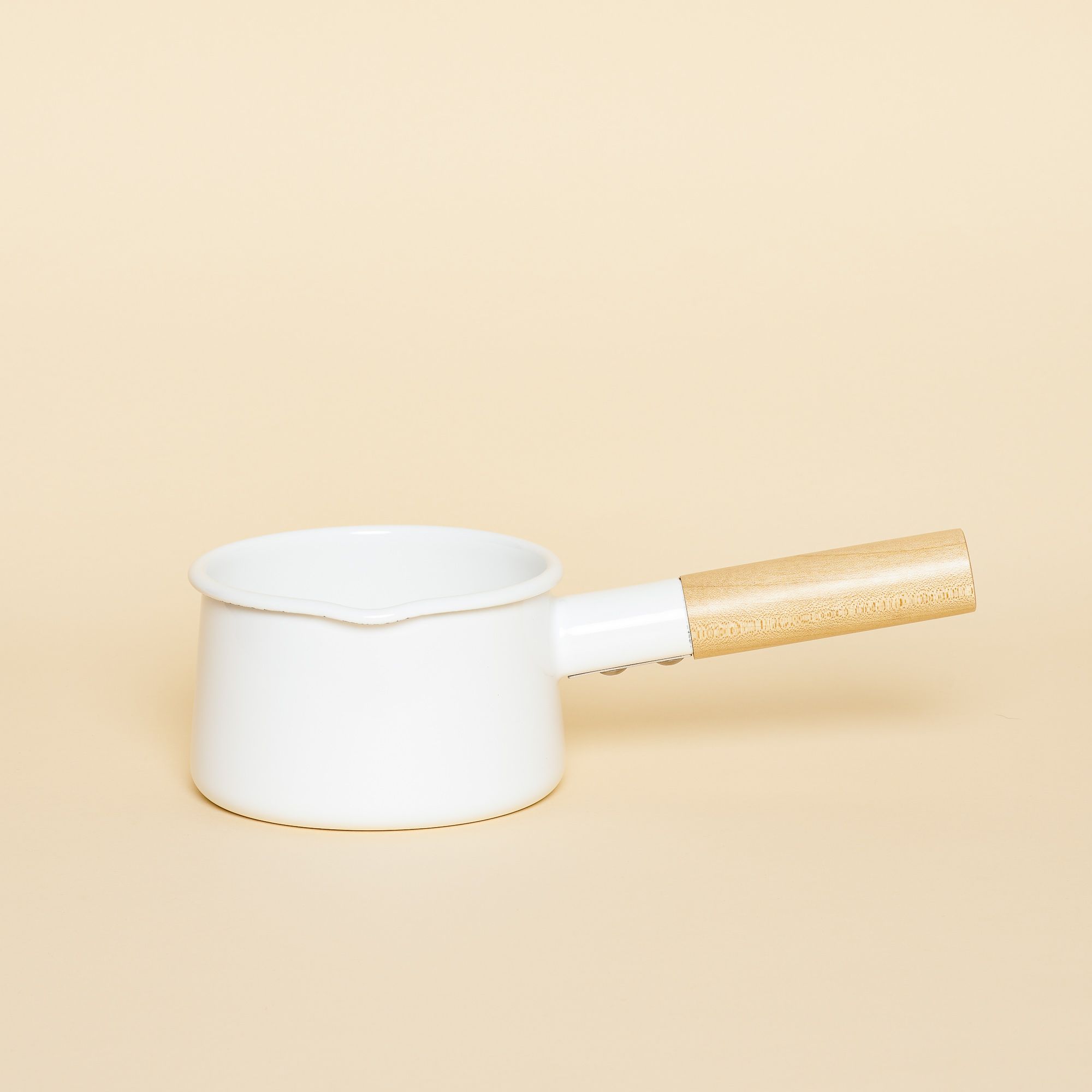 A small white enamel pan with a wooden handle. Sleekly designed.