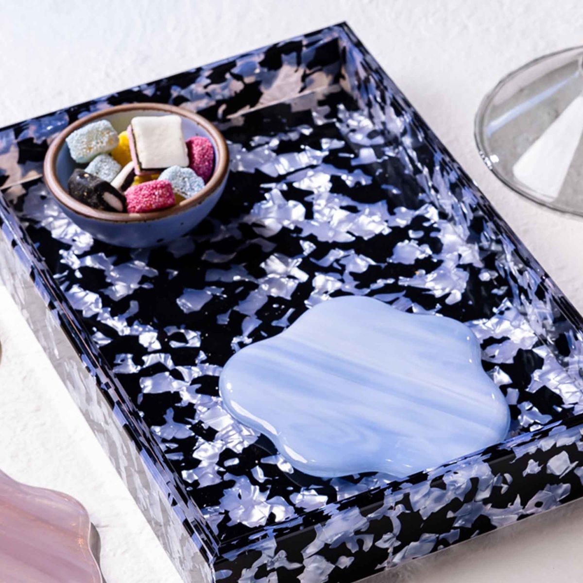 A rectangular acrylic tray with a black and light blue granite-like design with a coaster and tiny bowl in it