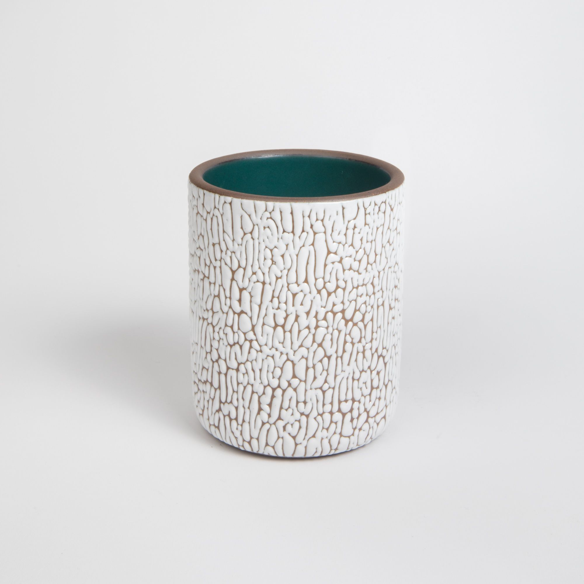 A big white ceramic vessel with cracked texture and the interior being dark teal