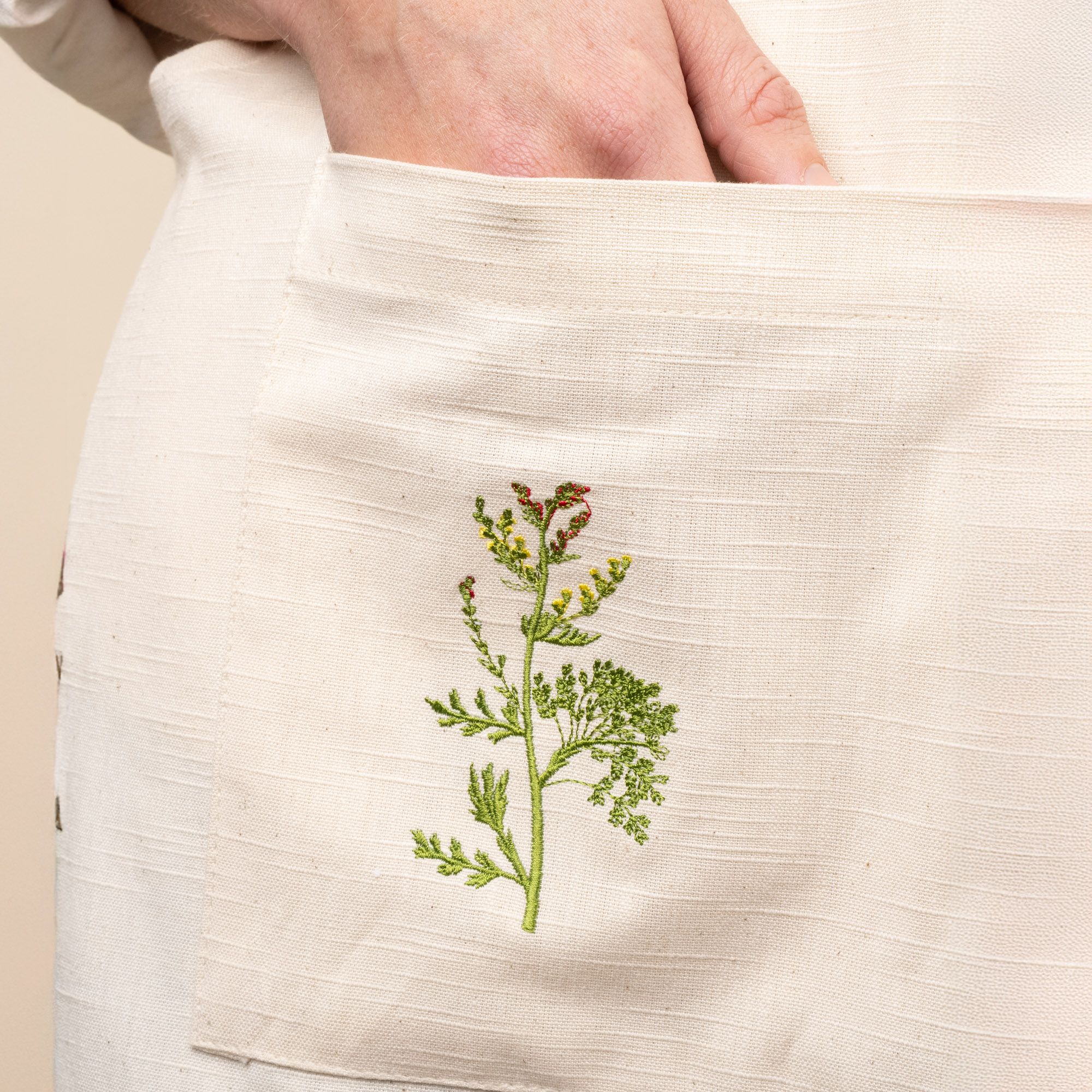 A close up of an embroidered flower on a canvas apron.