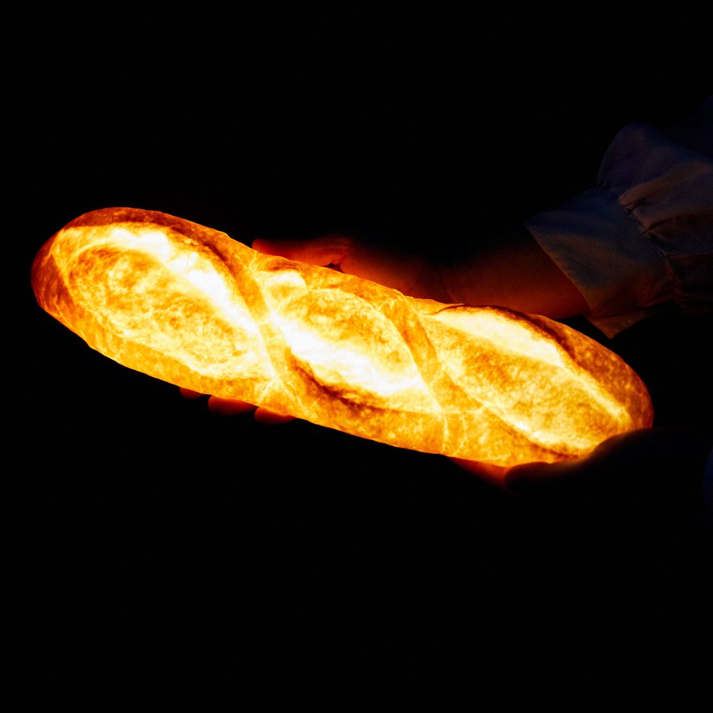 Hands holding a lamp that looks like a batard bread, glowing in the dark.
