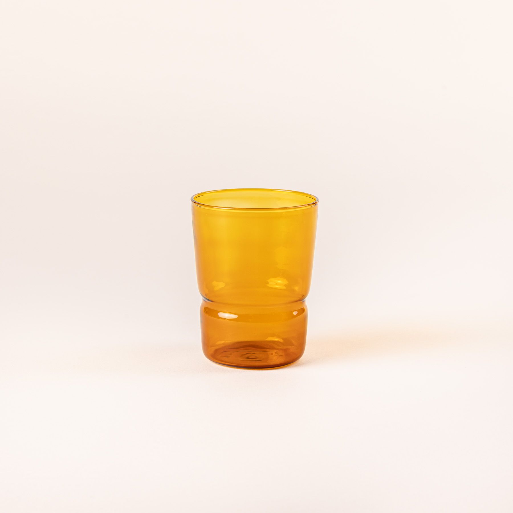 Tumbler glass that widens at the top in an amber color