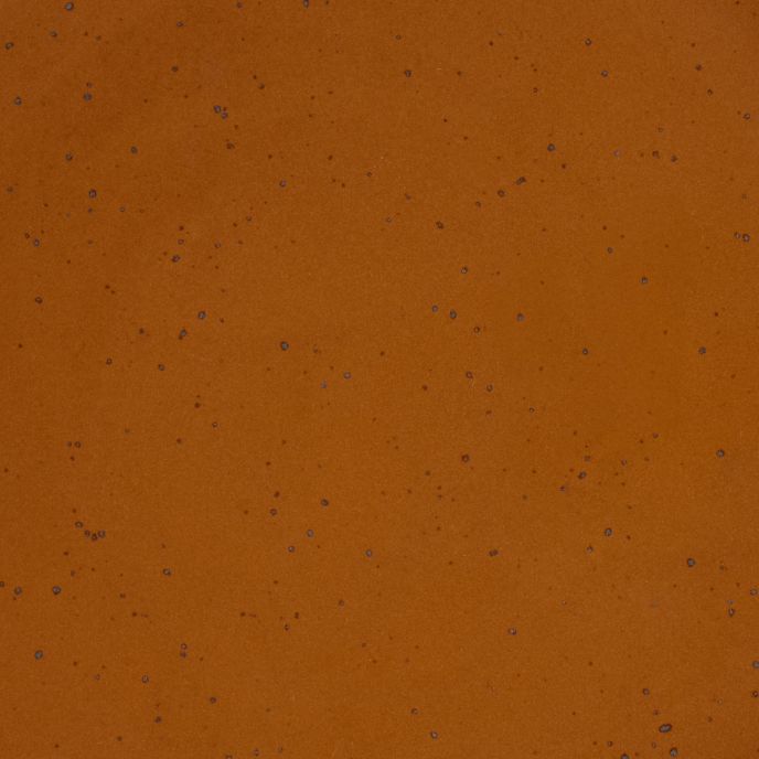 A closeup of a ceramic plate in a glossy caramel brown color with iron speckles throughout