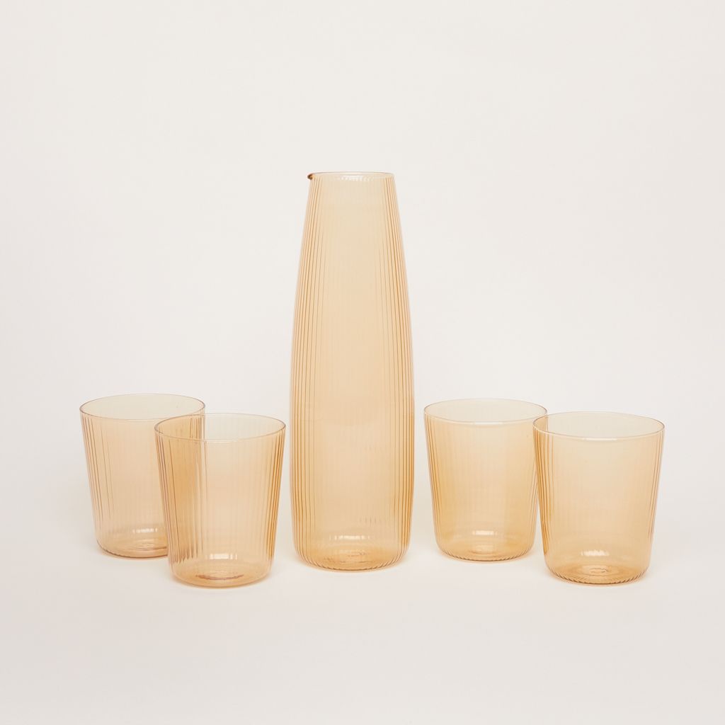 Four drinking glasses and a tall, cylindrical carafe, all in pale yellow glass