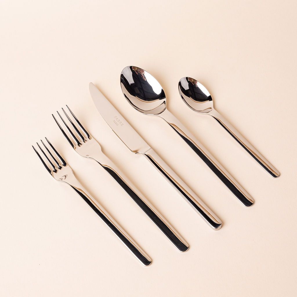 Classic minimal shiny stainless steel flatware arranged in a row with a salad fork, dinner fork, knife, spoon, and soup spoon.