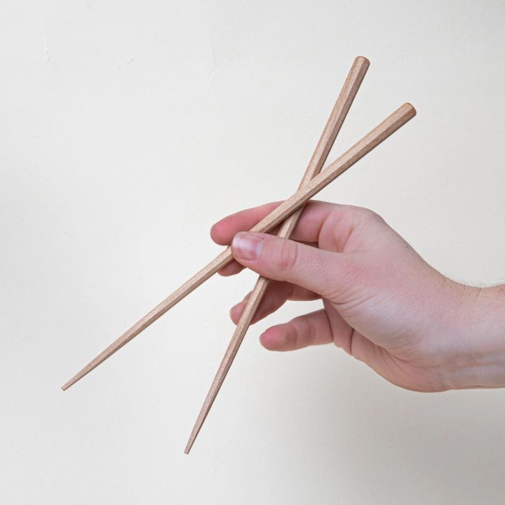 A hand holding simple light wood chopsticks