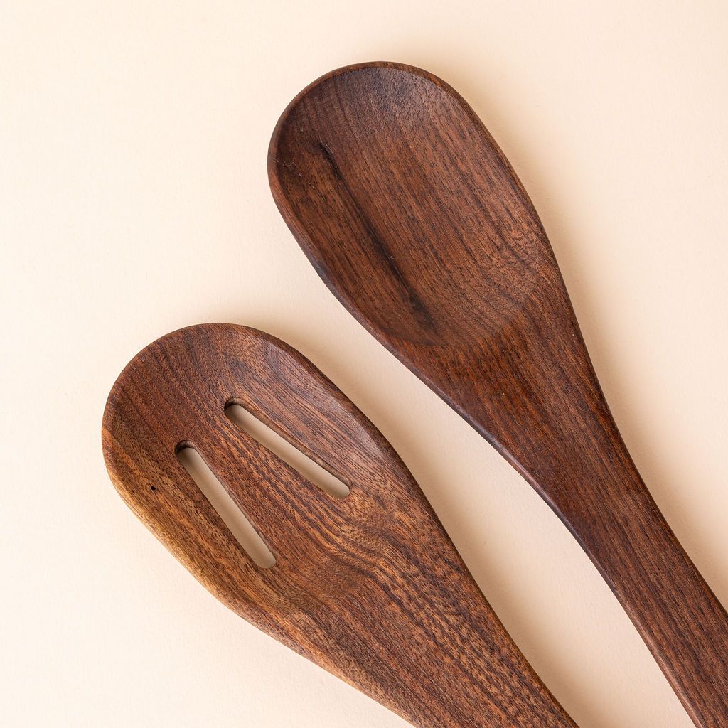 Close up of the top of two wooden spoons, the left has two slots and the right is solid.