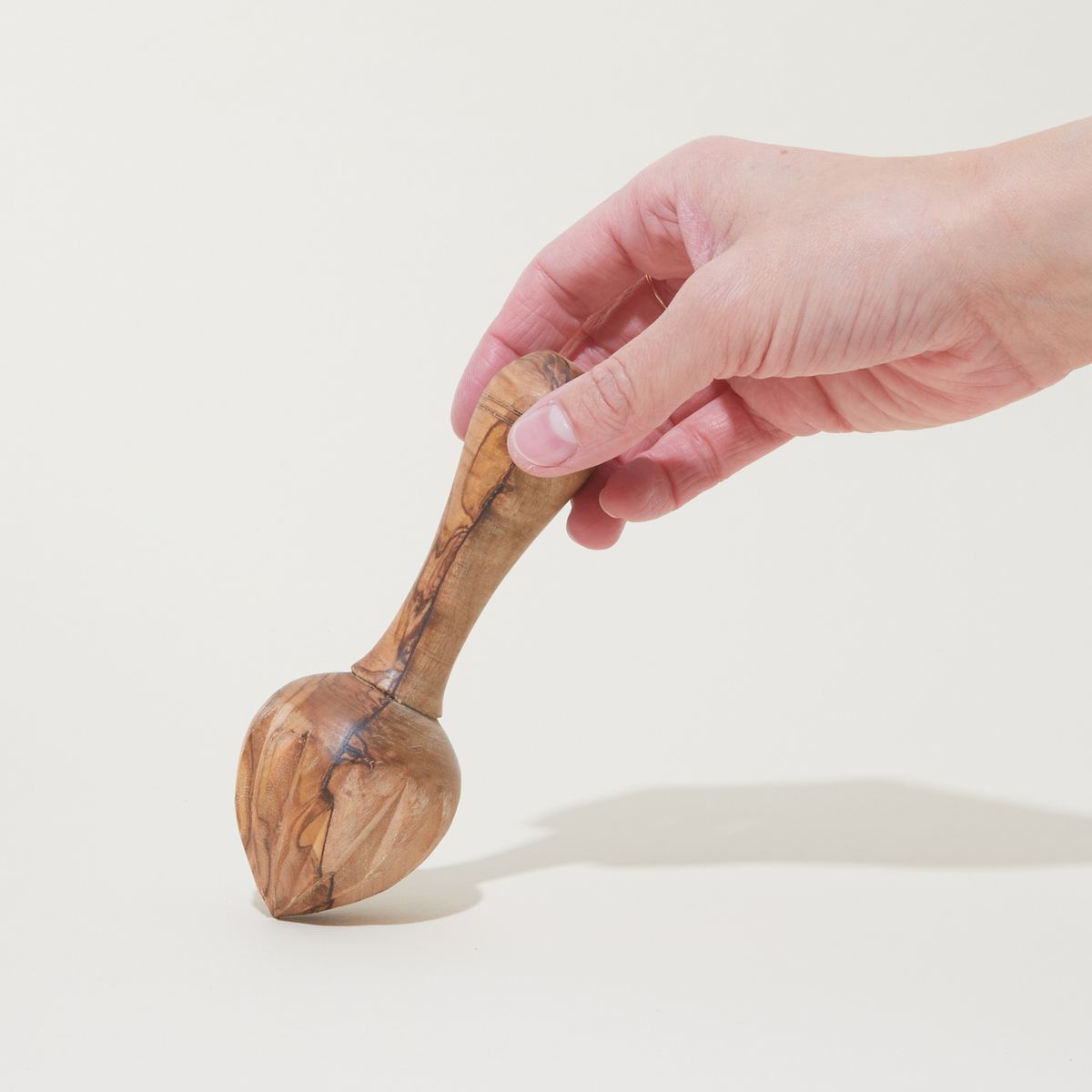 Hand holding a olivewood citrus reamer